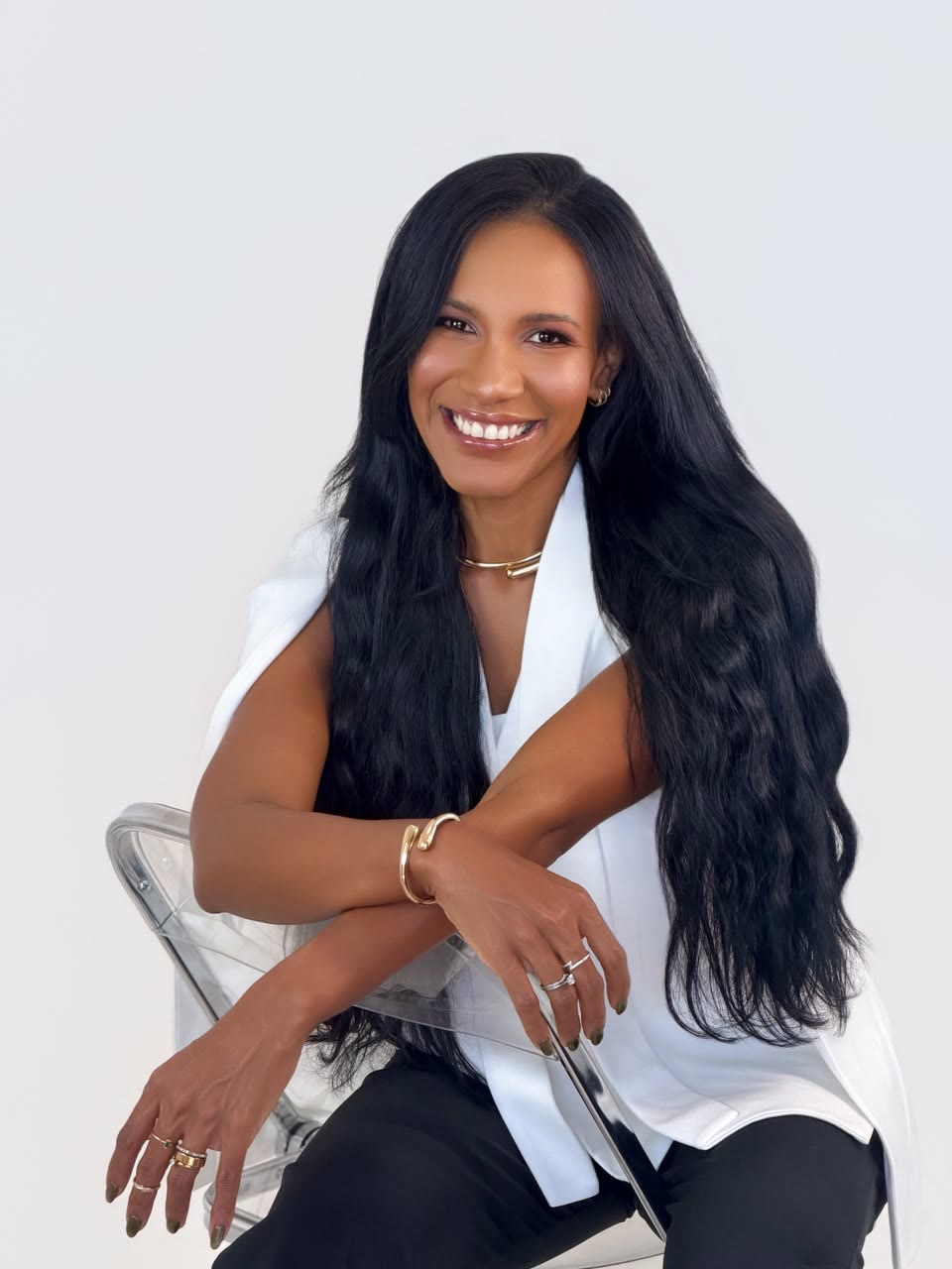 Elisabeth sentada, sorrindo, com os braços apoiados no encosto de uma cadeira